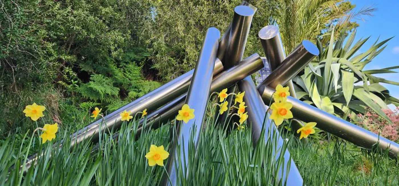 a group of metal poles surrounded by yellow flowers