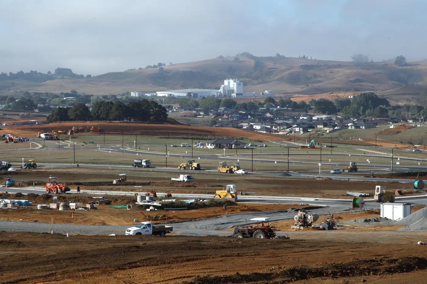 a construction site with many vehicles and buildings in the background