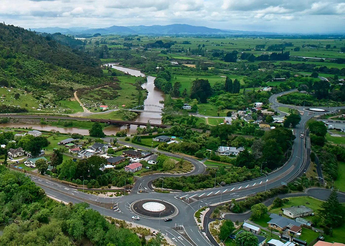 a road with a river and houses