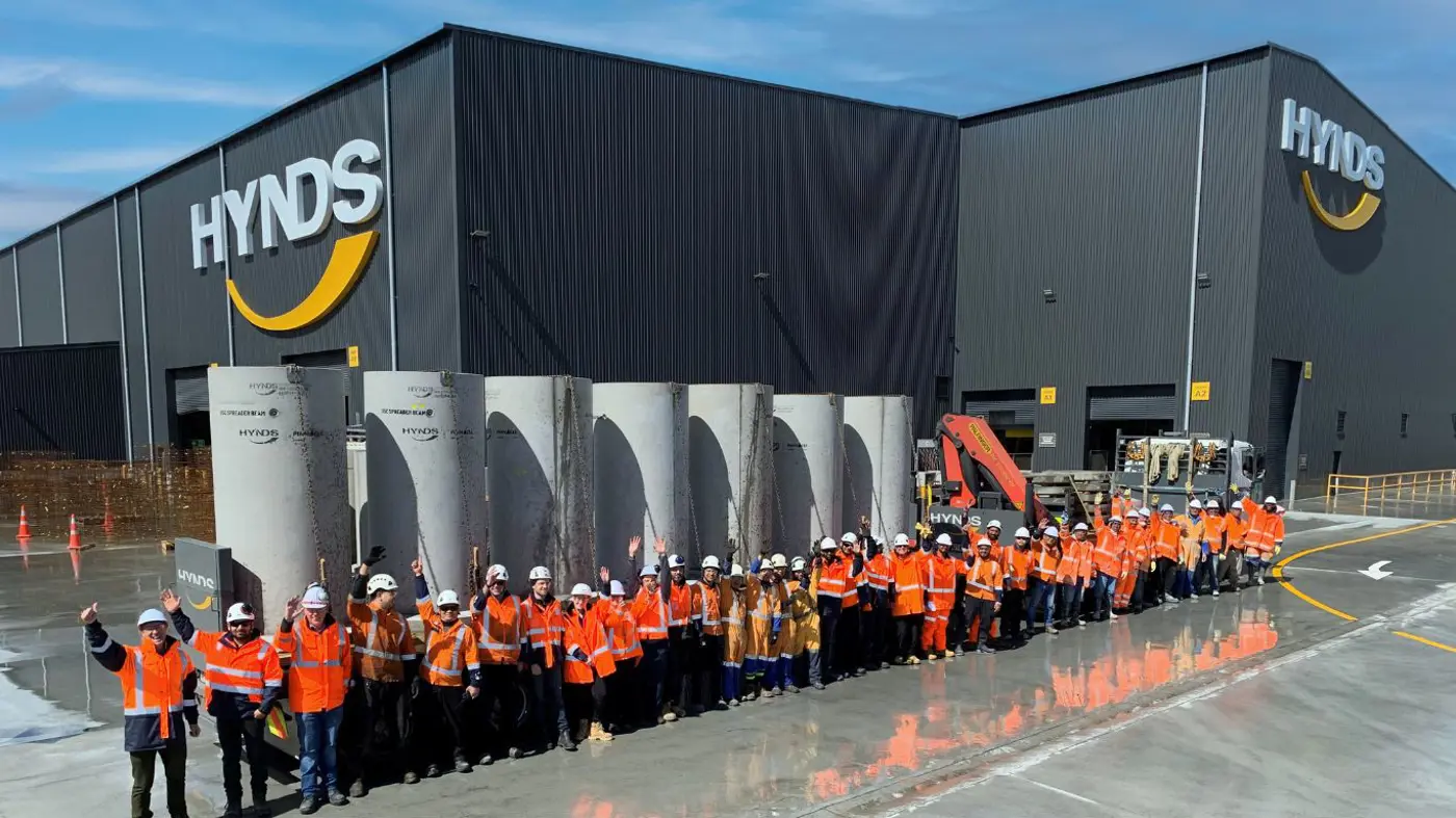 a group of people in orange vests and helmets standing in front of a building