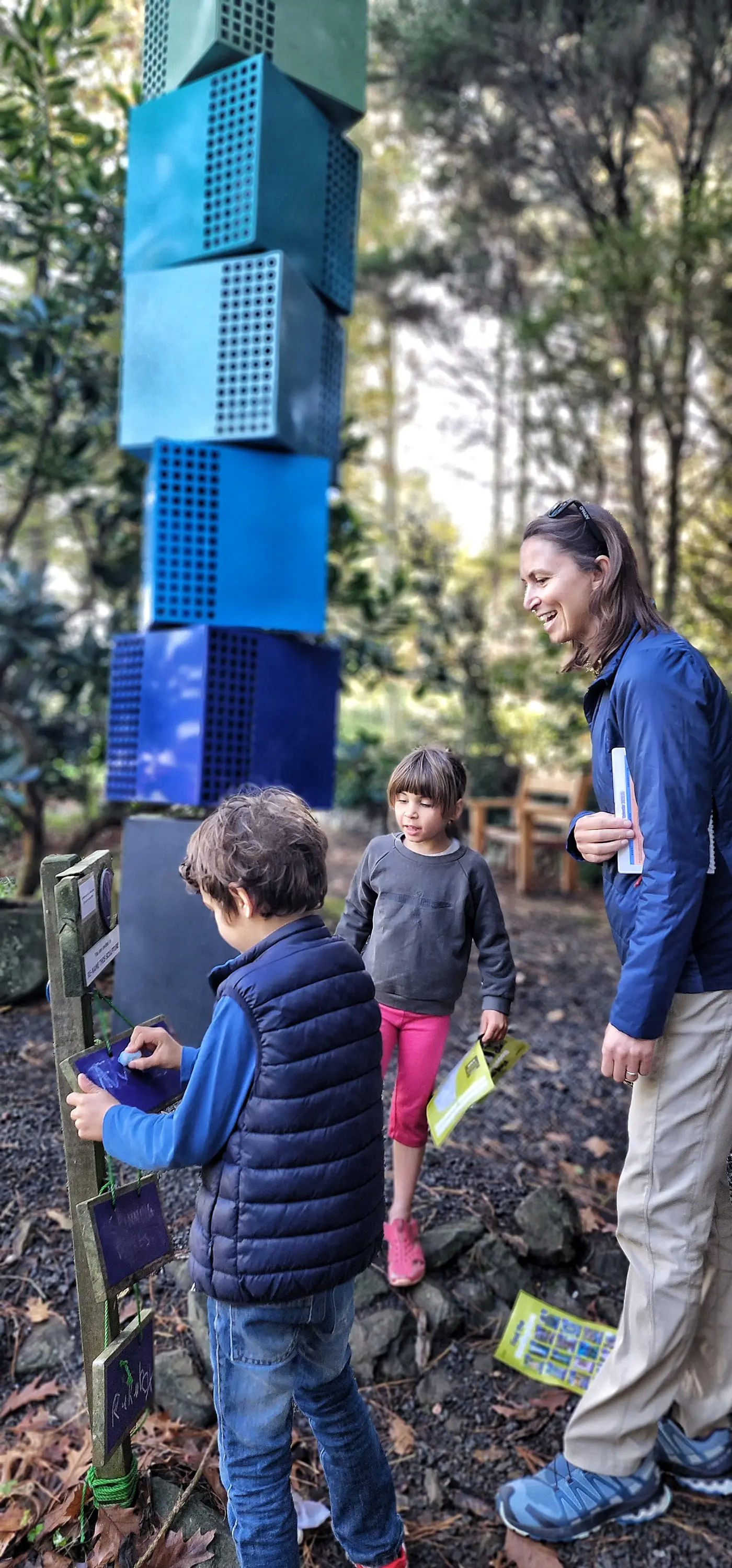 a woman and two children standing next to a blue box