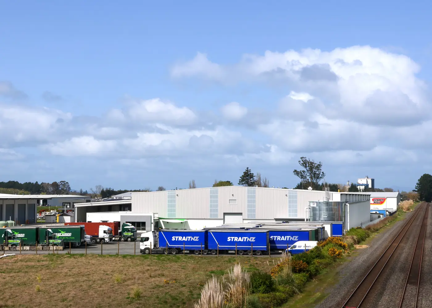 a warehouse with a train track and a building with trucks