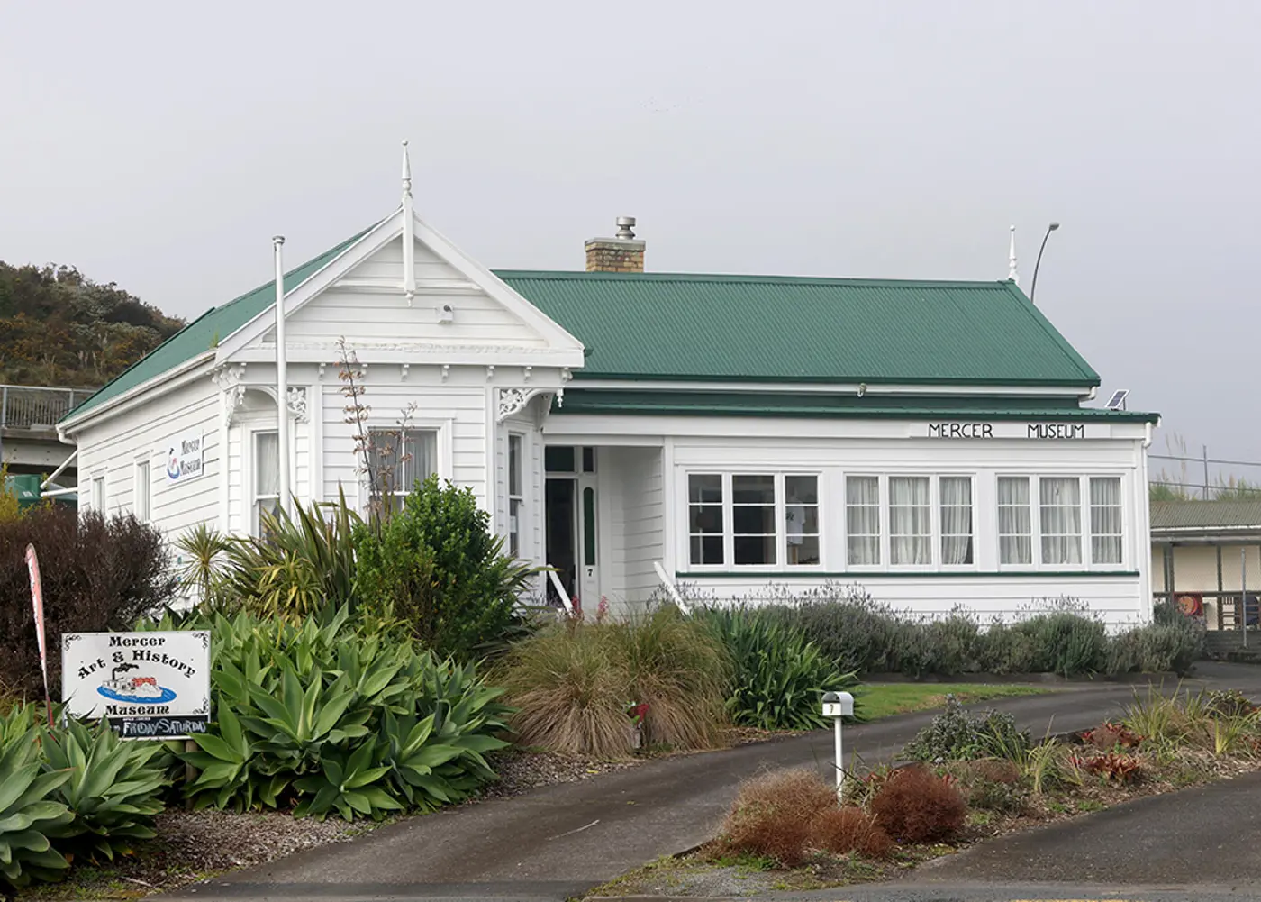 a white building with green roof and plants