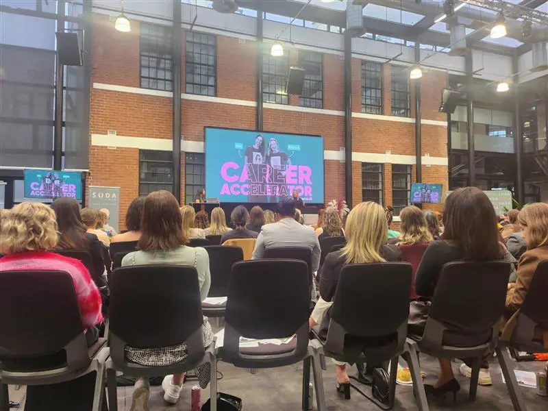 a group of people sitting in chairs in a room with a large screen