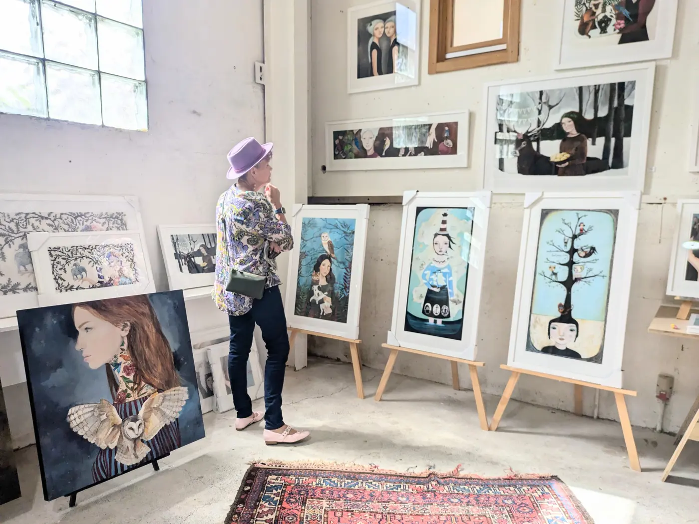 a woman looking at a group of paintings