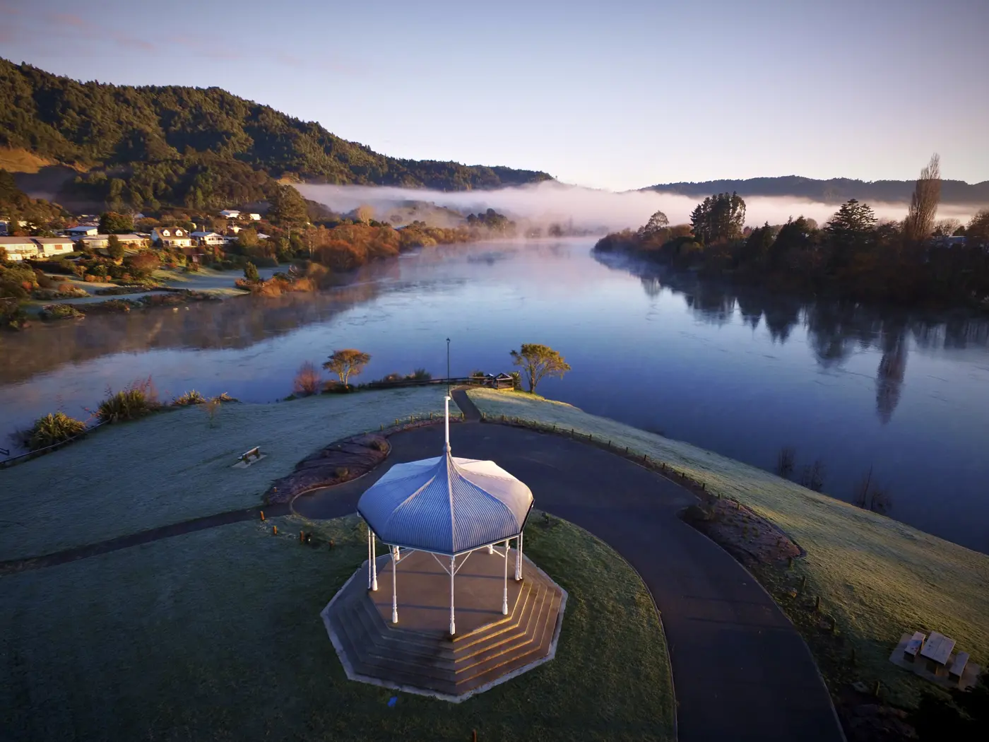 a gazebo on a grassy area by a river