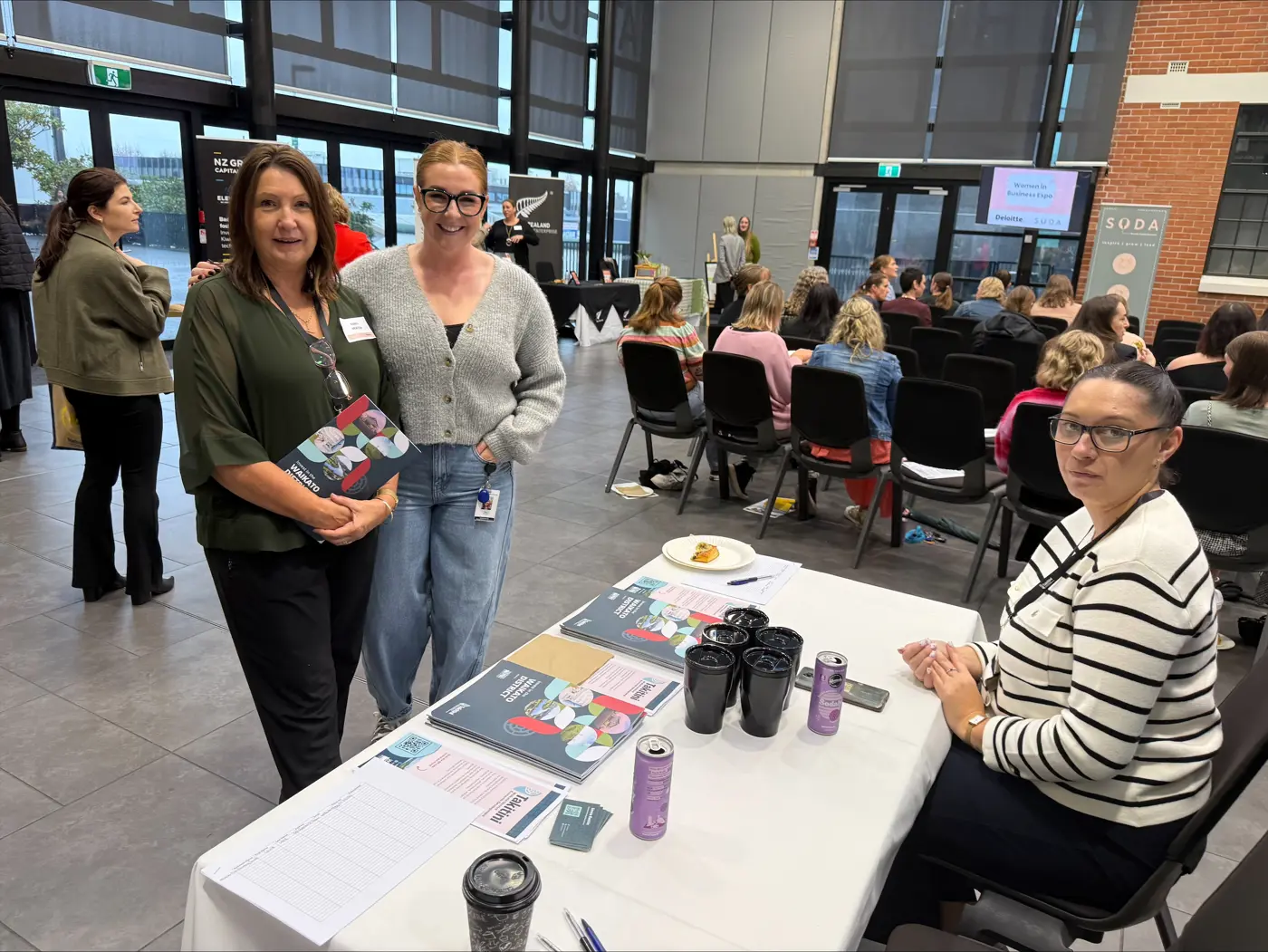 a group of women standing in a room with a table with a group of people