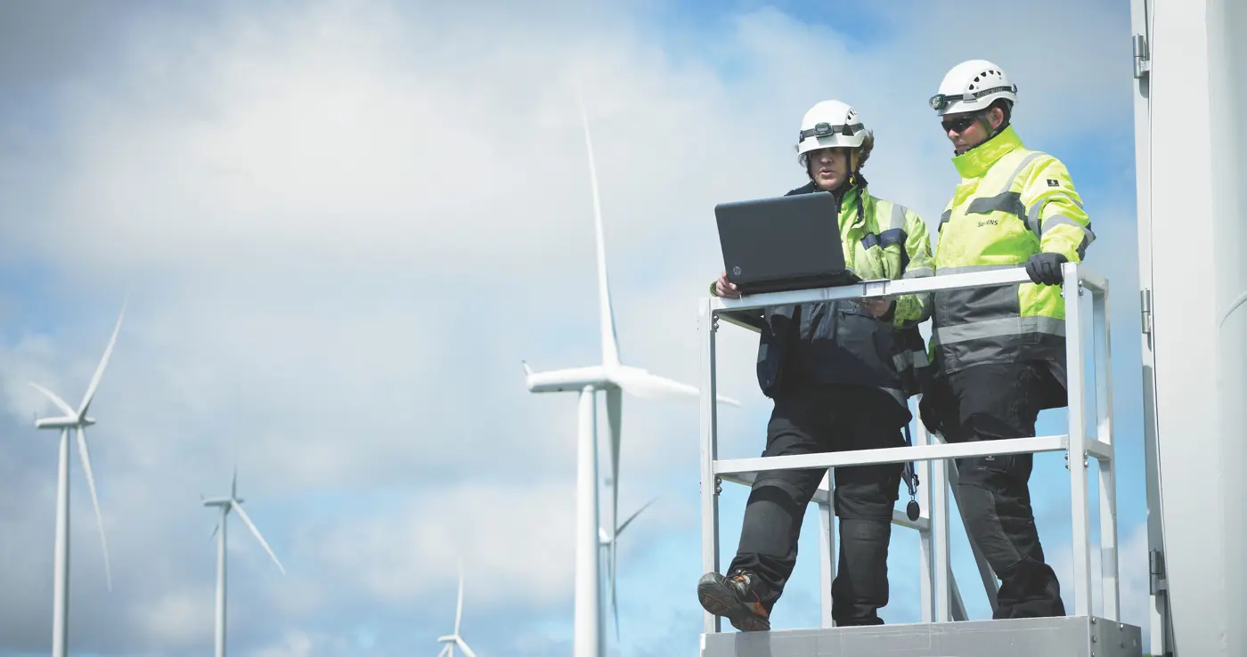a few men standing on a platform with a laptop
