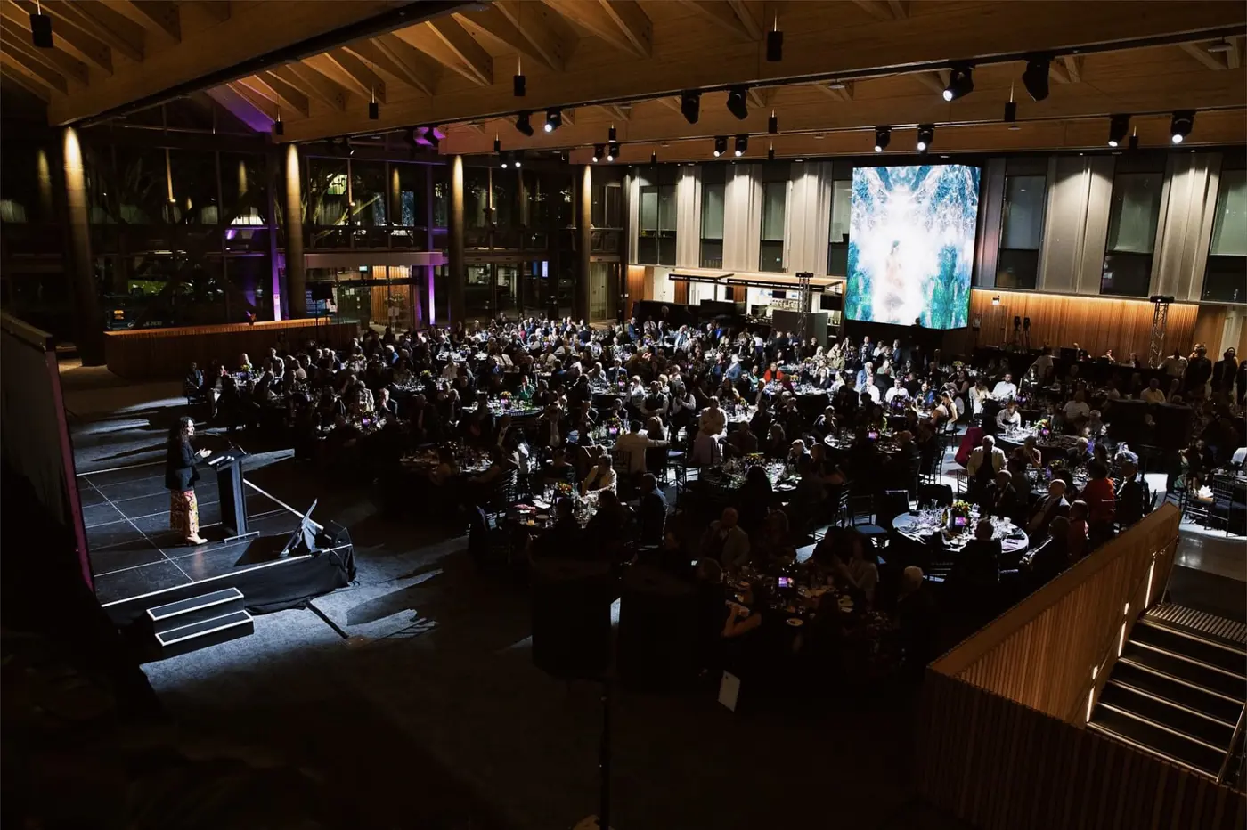 a large room with tables and chairs and a large screen